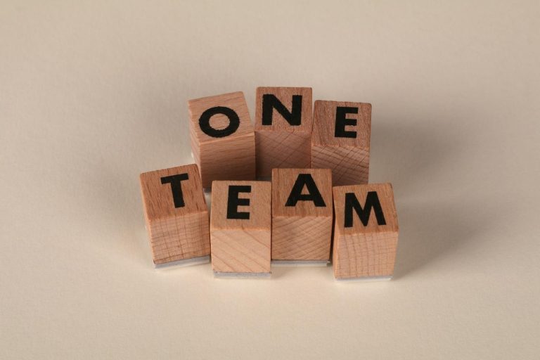 Wooden blocks spelling 'One Team', symbolizing teamwork and unity.
