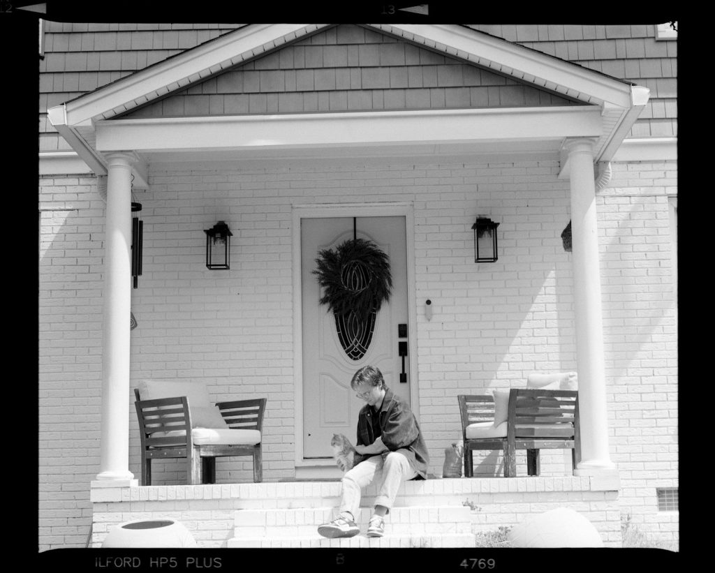 Young boy sitting on porch steps with dog.